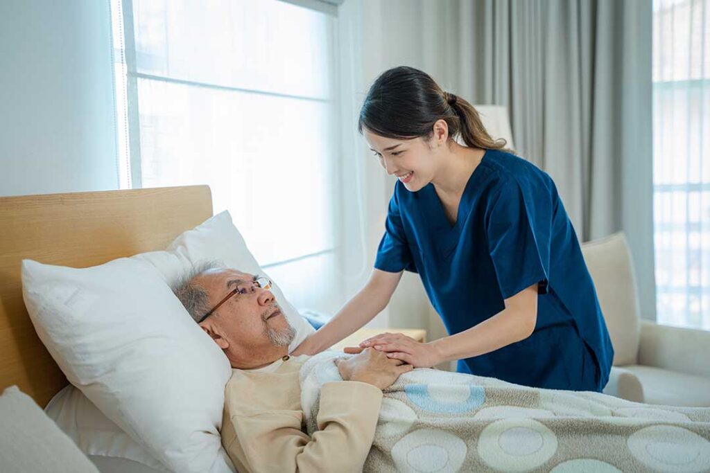 A middle-aged woman walks beside her elderly parent through a bright assisted living hallway, observing the surroundings together.